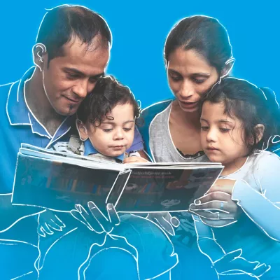 Romska porodica čita dečiju knjigu: majka i otac čitaju sinu i ćerki
