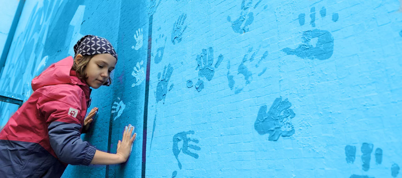 Girl painting UNICEF mural on the wall of her school in Belgrade, Serbia